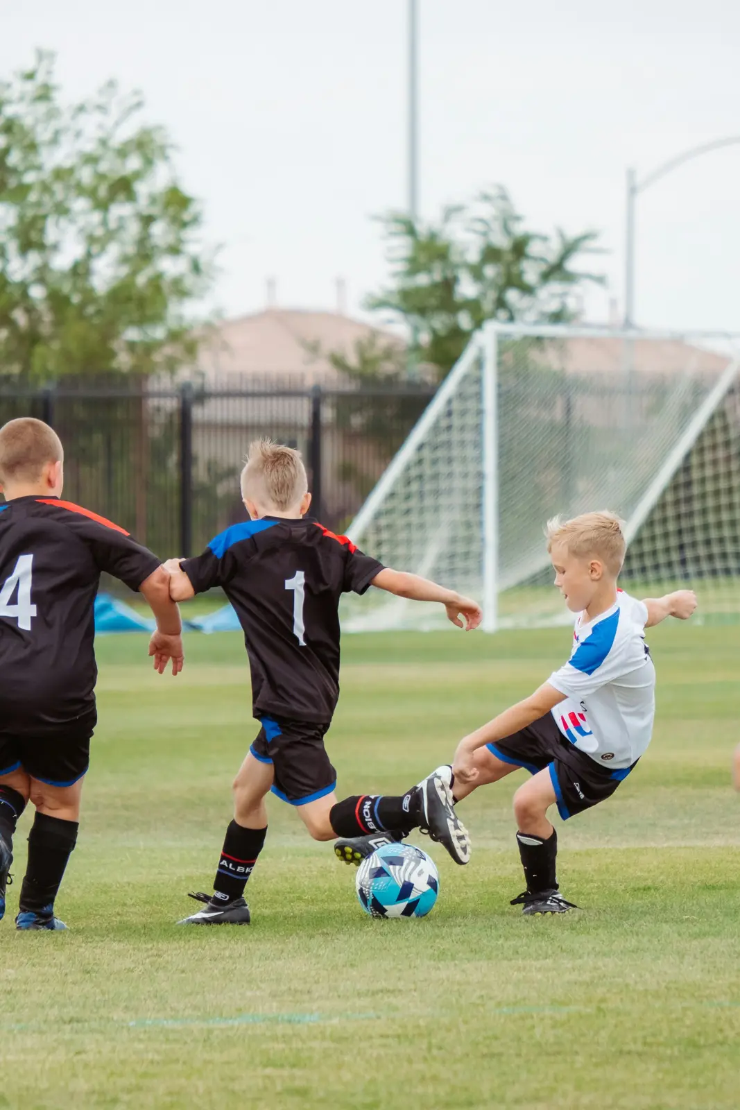 Three kids playing soccer on a grass field